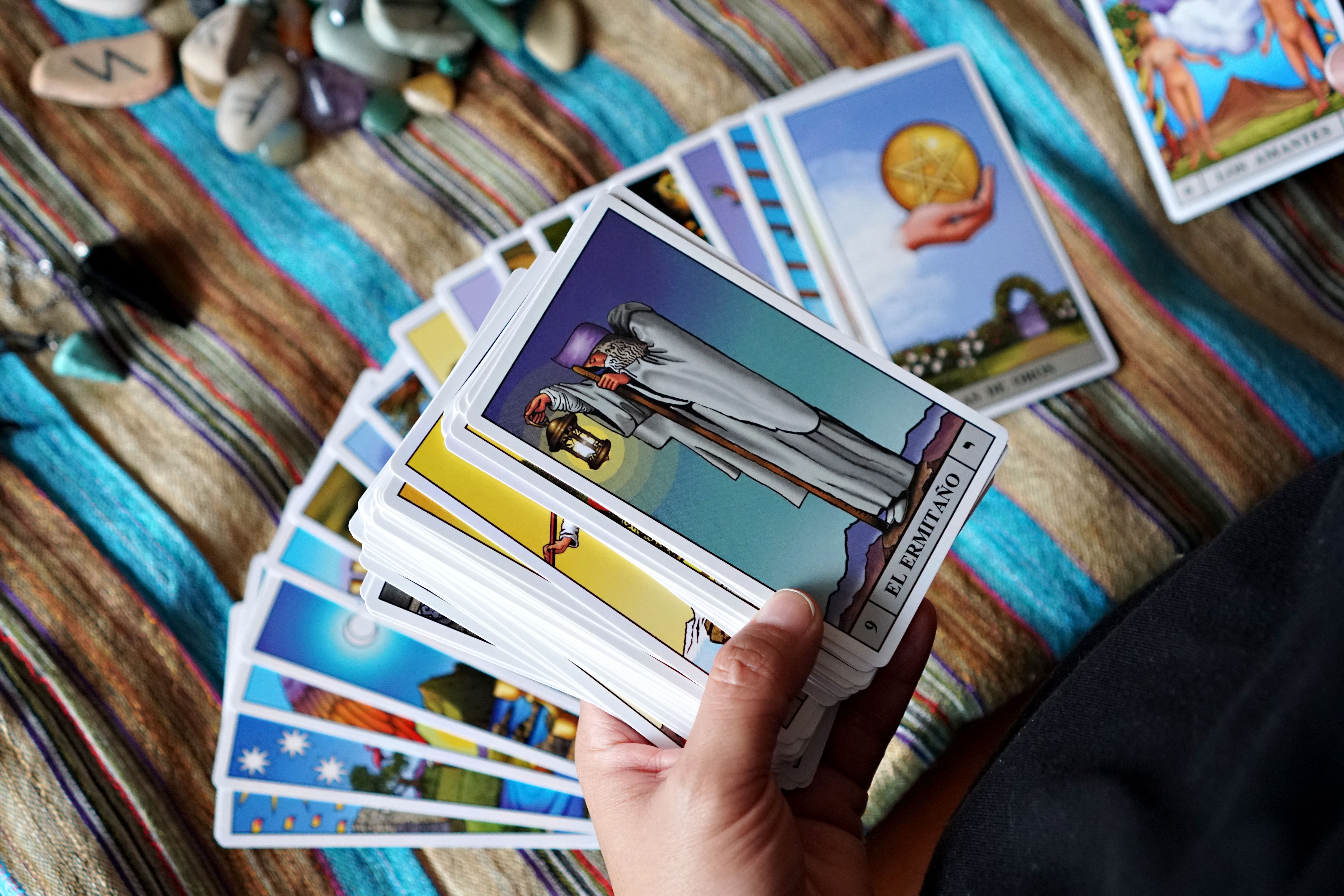 Hand holding a fanned deck of tarot cards with crystals and rune stones