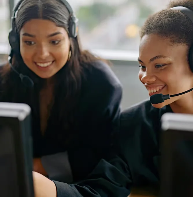 Two call-centre agents wearing headsets taking phone orders at their computers