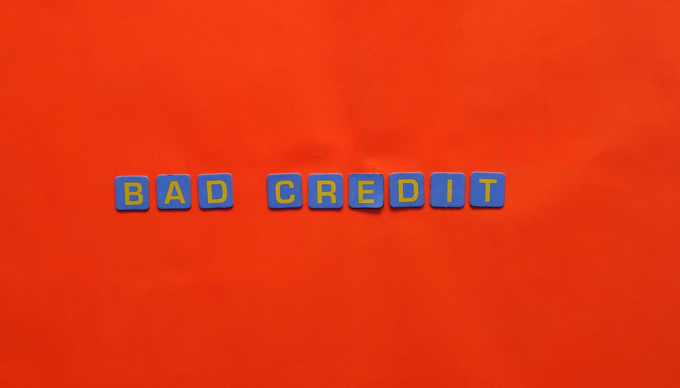 The words 'BAD CREDIT' spelled out in blue letter tiles with yellow letters on a bright orange background