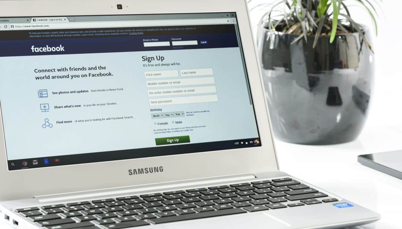 A laptop on a desk showing the Facebook sign-up page