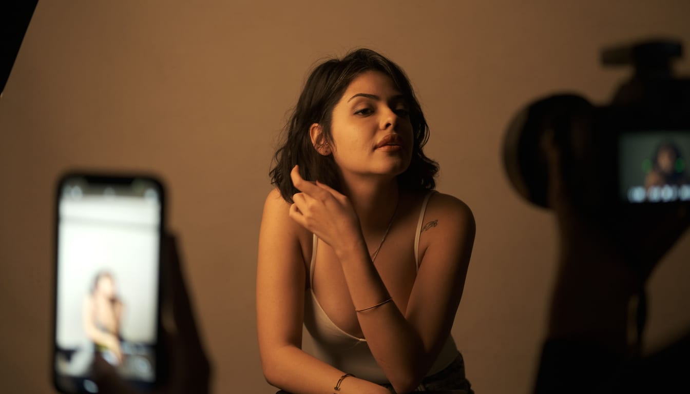 A content creator posing for a camera and phone during a studio shoot